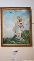 Full view of the framed oil painting showing a young girl reaching upwards with birds in the sky.