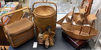 Full view of lot showing three woven baskets (including sailboat basket), three dolls, and wooden box on table