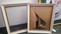 Two vintage painted wood frames, one with intact backing and one with torn backing paper, showing scratches and wear.