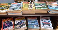 Top view of stacked vintage science and mechanics magazines with colorful illustrated covers featuring cars and mechanical topics.