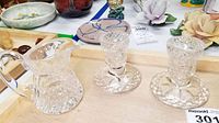 Full view of the Waterford crystal cream pitcher and two candle holders on wooden tray showing overall set condition and detail.