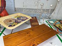 Photo showing metal serving tray with owl and floral design, carved wooden wall plate, two wooden wall shelves, metal wall shelf, and metal candle holder on floor.