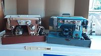 Both vintage commercial sewing machines with their cases, showing blue Arrow Automatic and brown Deluxe Automatic Zigzag machines side by side.