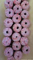 Top view showing the spiral arrangement of 20 full skeins and 1 partial skein of pink, white and coral variegated Cotton Tahiti yarn by Phentex, wound into balls.