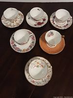 Top view of six English china teacups and saucers showing floral and patterned designs.