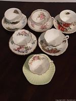 Top view of six teacups each on their matching saucer, showing various floral patterns and saucer shapes.