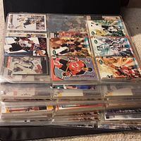 Top-down photo of binder open to several pages showing hockey cards arranged in 9-card sleeves with various players.