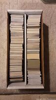 Box with two rows filled with trading cards stacked vertically showing card backs, indicating a large quantity of cards.