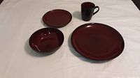 Set of one dinner plate, one small plate, one bowl, and one cup displayed on white background showing color and shape.