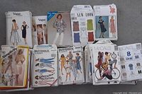 Photo showing an assortment of ladies sewing patterns from Vogue, New Look, Style, Simplicity, Butterick, and McCall's with visible illustrations of dresses, tops, pants.