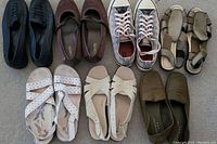 7 pairs of ladies size 10 shoes and sandals laid out on carpet floor showing various styles and colors.