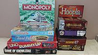 Photo showing stacked board games including Ms. Monopoly sealed, Monopoly classic, Trivial Pursuit DVD Culture, UNO, Rummy Up, Game of Knowledge