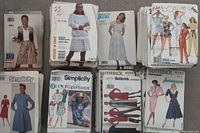 Multiple stacks of vintage and modern Butterick, McCall's, and Simplicity women's sewing pattern envelopes showing a variety of garments such as dresses, skirts, sportswear, and casual wear.