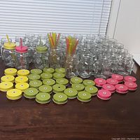 Photo showing all 38 mason jar glasses arranged with lids placed in front and straws in some jars