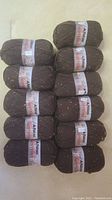 Lot of 11 skeins of Patons Classic Wool Tweeds yarn arranged together on a light surface, showing the brown yarn with colorful flecks.