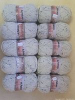 Top view of 10 skeins of Patons Classic Wool Tweeds yarn in cream/off-white with black speckles, arranged in rows