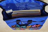 Top view inside blue craft bag showing assorted 12x12 scrapbooking sheets in inner compartment