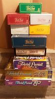 Stack of 10 boxed Trivial Pursuit games including Genus III, Genus IV, and multiple classic editions by color.