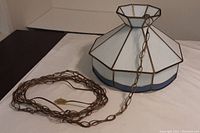 Photo of the vintage hanging slag glass lamp showing 8-panel design, marbled white glass with blue trim, and long chain with plug.