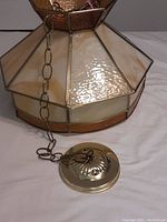 Close-up view of slag glass panels, amber glass trim, brass framing, chain and ceiling mount.