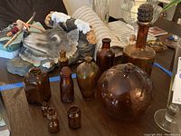 Overview of amber glass jars in various shapes and sizes on a table, showing a large spherical jar, rectangular and cylindrical jars, some with narrow necks.