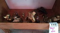 Wood shelf holding a variety of small brass animal figurines, including duck, dog with top hat, cat, boot, and shoes.