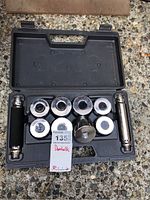 Top-down view of the open black carrying case containing the adjustable dumbbell set, showing two chrome handles, eight weight plates, and a label.