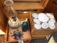 Photo showing the hurricane lamp, blue glass jar, assorted beach glass, coral piece, and sand dollars on wooden crates.