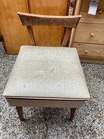 Front view of sewing chair showing upholstered seat with stains and tear.