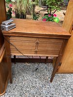 Wooden sewing table with Kenmore sewing machine on top, showing front side with drawers and visible wear.