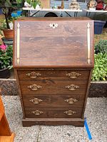 Closed wooden stereo console cabinet with fold-out desk front and brass hardware.