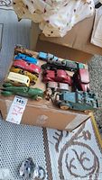 Overview of vintage die cast metal toys including several cars, camper, toy train engine, and toy men.
