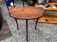 Front-top view of the vintage wooden side table showing stains and water marks on the tabletop and its three curved legs.
