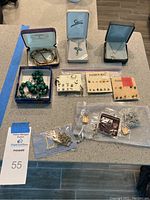 Full lot showing all jewelry pieces arranged on countertop, including boxes and plastic bags with earrings.