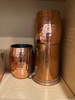 Two hammered copper Moscow Mule mugs stacked, one with handle