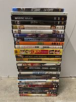 Stack of 26 DVDs and Blu-ray movie cases showing varied titles and genres.