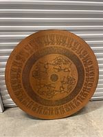 Full front view of the copper art piece showing the entire circular design with chariot and figure engravings.