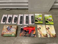 Overview of all items including 7 remote controls, NERF toy gun, Neighborhood Maker set, two Brica kick mats, and two books.