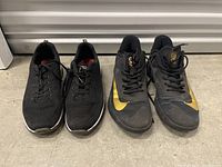 Both pairs of Nike shoes side by side on the floor, showing front and side profiles for size and condition.