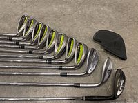 Row of all clubs laid on concrete floor with one headcover