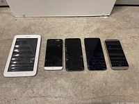 Five devices including Samsung tablet and four smartphones visible on floor surface