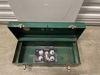 Open green metal toolbox showing inside bottom and the golf gift set container stored inside