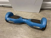 Full view of blue Zyro hoverboard front with black footpads and single wheel on each side, showing condition and wear.