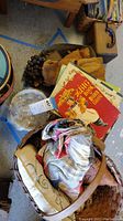 Contents of lot showing vintage book, baskets, fabrics, and baseballs.