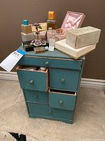 Full view of turquoise chest topped with various perfume bottles and boxes