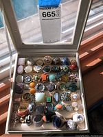 Beige jewelry box with clear lid open showing all rings in grid layout