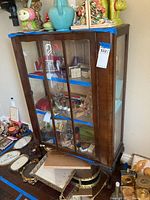 Front view of wooden curio cabinet with glass shelves and display contents inside (not included).