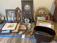 View of collection showing multiple framed artworks, decorative fan, empty frames, small framed pictures, and wood box on legs