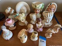 Front view of 14 assorted head vases arranged on table