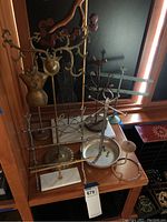 Group photo showing seven assorted metal jewelry stands placed on a wooden shelf.